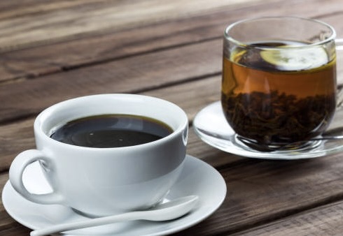 cup of tea with lemon and a cup of coffee on a wooden surface, the choice between coffee and tea